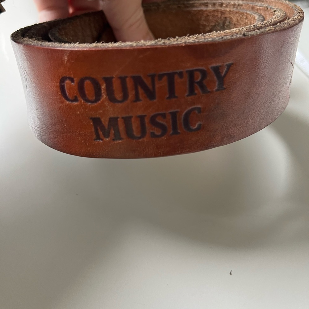 Tan leather country music belt with instruments imprinted in the leather